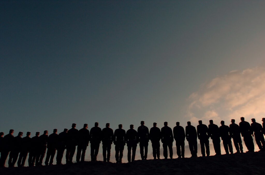 Silhouetted line of Navy trainees against a dark dusk sky