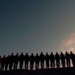 Silhouetted line of Navy trainees against a dark dusk sky